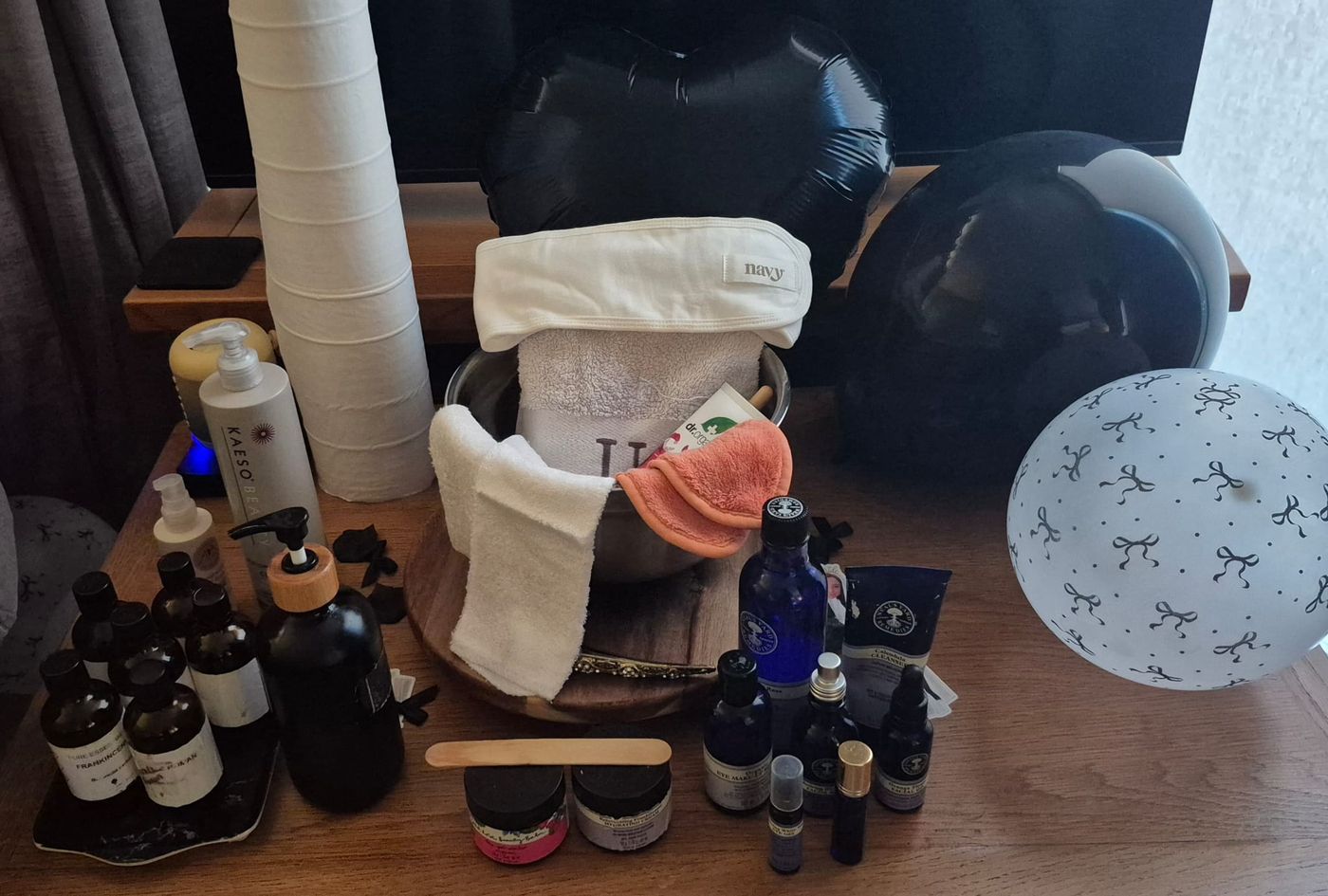 Skincare products, essential oils, towels and a headband laid out on a sideboard