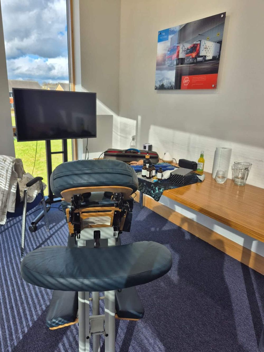 The massage chair set up in a meeting room beside a table of oils and towels