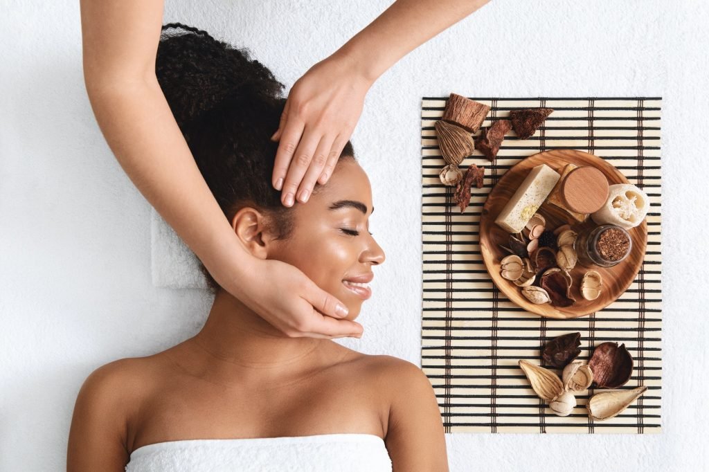 Peaceful african american woman enjoying facial massage at spa